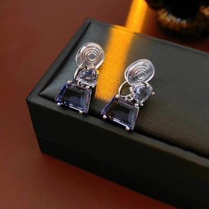 Macro shot of geometric purple zircon earrings on a black leather jewelry box background