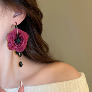 Macro view of long dark red fabric rose earrings with hanging black crystal drop beads
