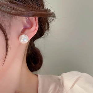 Close-up of a large elegant round pearl stud earring worn by a model with soft lighting