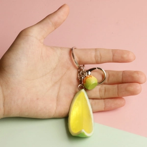 Detailed view of PVC lemon slice keychain held by hand to show actual scale and texture