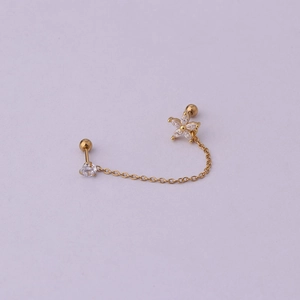 Detail of gold chain earring with sparkling zircon flower and single stud on purple base