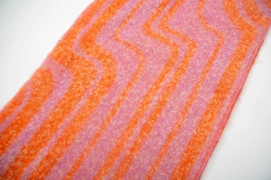Detail of soft orange and pink wavy jacquard knit fabric with fluffy boucle texture