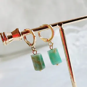 Detail view of cylindrical green natural stone earrings with golden circular hoops