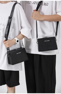 Detail view of black box crossbody bag featuring smooth and crocodile texture on models