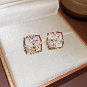 Macro shot of pink enamel square earrings with pearls and crystals on silk background