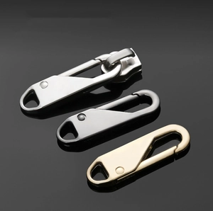 Macro shot of silver, gunmetal, and gold metal zipper pulls showing glossy alloy texture