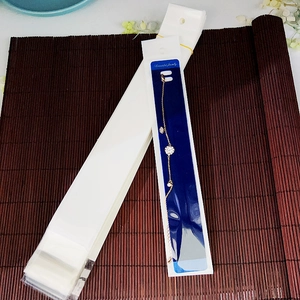 Dettaglio del cartoncino bianco per gioielli con un bracciale dorato impreziosito da strass