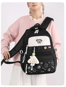 Close-up of waterproof nylon school backpack with cute bear print and floral pendant charms