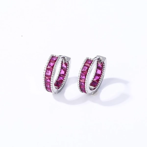 Macro detail of silver hoop earrings with square-cut red zircon stones on white background