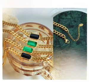 Detail of gold Cuban chain necklace with emerald green stone and adjustable lobster clasp