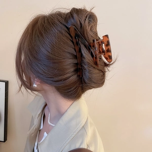 Macro view of leopard print acrylic shark hair clip holding a bun hairstyle securely