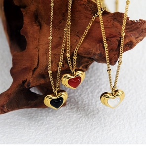Three elegant heart necklaces in black, red, and white with golden ripple edges on wood