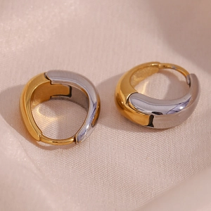 Macro detail of high-polish two-tone gold and silver minimalist huggie hoop earrings