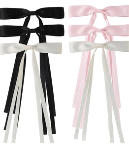 Detail view of six satin ribbon hair clips in black, pink, and white colors