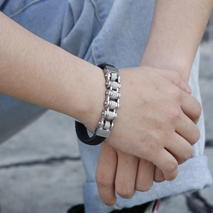 Detail of punk style bike chain bracelet with knurled metal and black woven leather cord