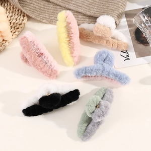 Variety of plush cross-shaped hair claws in vibrant mixed colors on a cozy table