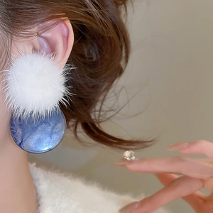 Detail of white pom-pom and blue marble texture drop earring on a female model