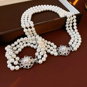 Macro detail of multi-strand pearl necklace with diamond-encrusted flower metal buckles