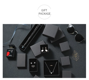 Flat lay of elegant matte black gift boxes for necklaces and rings on grey background