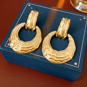 Close-up of golden textured circular earrings on a blue star-patterned jewelry box