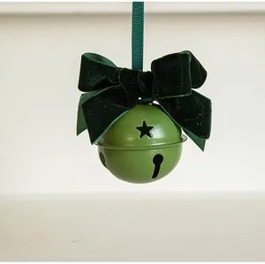 Detailed view of matte green metal bell with premium dark green velvet bow and star cutouts