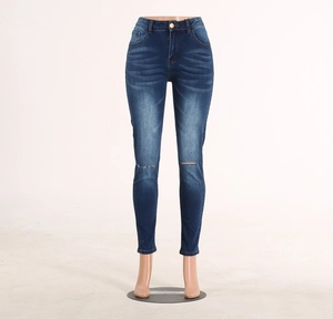 Detail of dark blue skinny jeans featuring whiskers wash effect and ripped knees