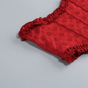 Detailed macro view of red lace embroidery and ruffled hem on elegant off-shoulder dress