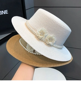 Detail of straw sun hats with pearl chains and sequin flowers in white and natural tones
