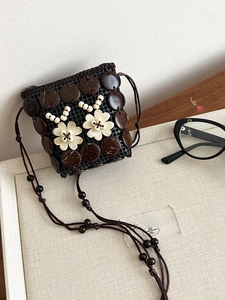 Detail of handmade bohemian coconut shell crossbody bag with white flower accents
