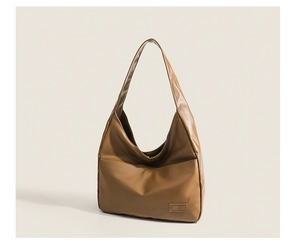 Close-up of a brown synthetic leather tote bag with a minimalist shoulder strap design