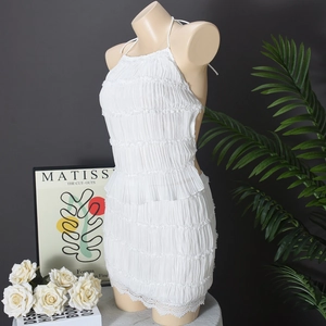 Detail of white ruffled halter mini dress with delicate lace trim on the hemline