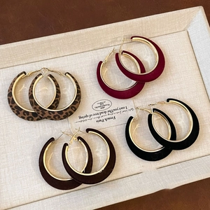 Detail view of velvet C-shape hoop earrings in leopard print, burgundy, brown, and black