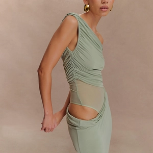 Detail of light green ruched dress featuring asymmetric cutouts and sheer waist mesh