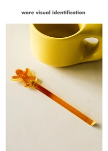 Macro detail of amber glass gingerbread man stirrer with heart buttons in coffee mug