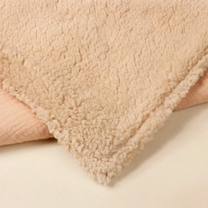 Close-up of thick beige faux lamb wool and pink muslin cotton fabric for baby blanket
