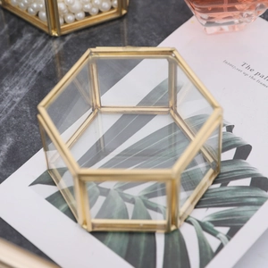 Elegant hexagonal brass glass jewelry box with lid on marble surface with accessories