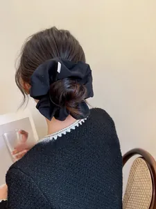 Detail of black fabric hair scrunchie with silver rhinestones on a high ponytail