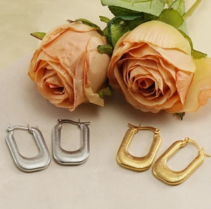 Détail macro de boucles d'oreilles en U dorées et argentées avec texture nervurée