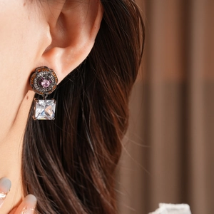 Close-up of vintage flower earrings with pink gemstone and square zircon drop