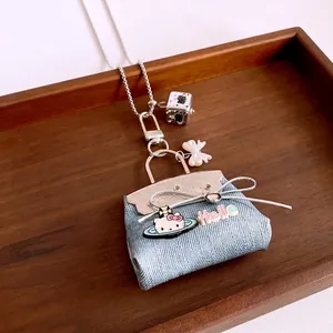 Blue denim mini bag pendant necklace with Hello Kitty design on a wood tray