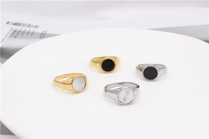 Flat lay of four minimalist round signet rings with shell inlay on a white tray