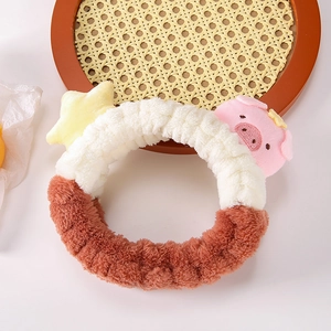 Gros plan d'un bandeau en peluche avec cochon et étoile et bracelets assortis