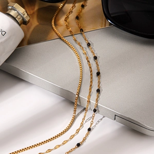 Detail of triple-layer gold stainless steel necklaces with black beads on laptop