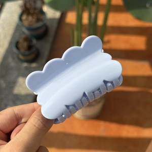 Macro detail of a light blue matte resin hair claw clip with a wavy edge design