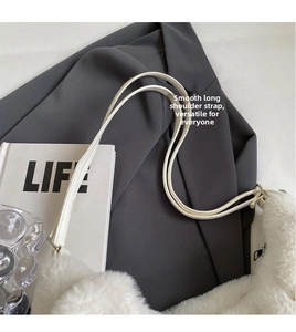 Detail view of the plush faux fur texture and long leather shoulder strap on the white bag