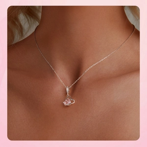 Close-up of pink heart-shaped gemstone pendant on silver chain worn by a model
