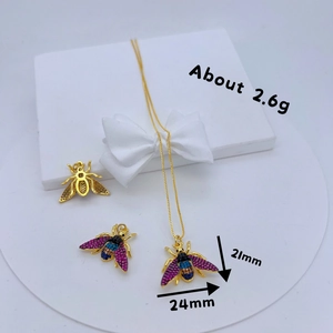 Gold bee pendant with inlaid colorful rhinestones on a white gift box base