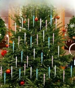 Detailed view of pink, blue, and clear acrylic icicle ornaments hanging on a Christmas tree