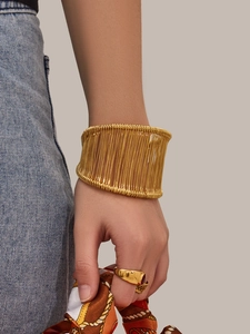 Détail d'un large bracelet doré en fil enroulé et d'une bague sur le poignet