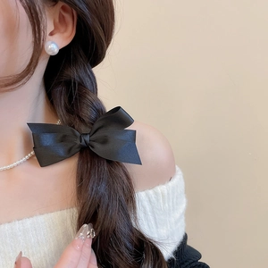 Barrette nœud en satin noir élégante portée sur une tresse latérale style vintage chic